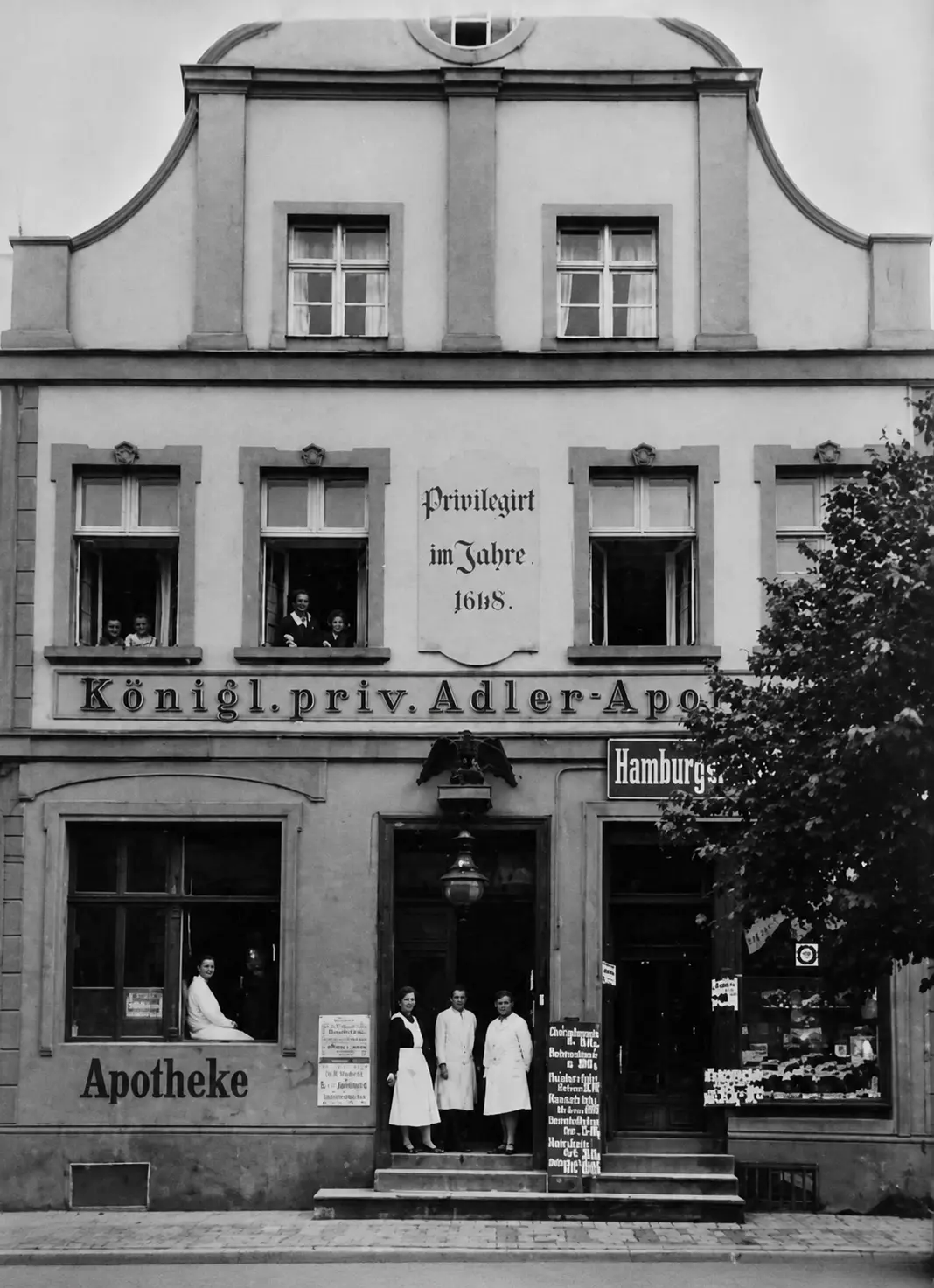 Archiwalna fotografia fasady apteki z personelem przed wejściem